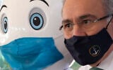 Brazilian Health Minister Marcelo Queiroga stands next to the mascot promoting the vaccination campaign as he gives shots of the AstraZeneca COVID-19 vaccine at a vaccination center in Brasilia, Brazil, Wednesday, July 14, 2021. (AP Photo/Eraldo Peres)