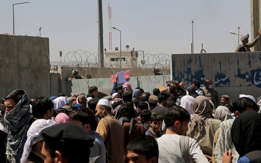 US soldiers stand inside the airport wall as hundreds of people gather near an evacuation control checkpoint on the perimeter of the Hamid Karzai International Airport, in Kabul, Afghanistan, August 26, 2021. (AP Photo/Wali Sabawoon)