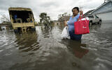A woman returns to her destroyed home with the assistance of a Louisiana National Guard high-water vehicle to retrieve medicine for herself and her father, and a few possessions, after she evacuated from rising floodwater in the aftermath of Hurricane Ida in LaPlace, Louisiana, August 30, 2021. (Gerald Herbert/AP)