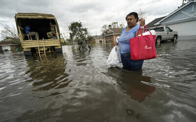A woman returns to her destroyed home with the assistance of a Louisiana National Guard high-water vehicle to retrieve medicine for herself and her father, and a few possessions, after she evacuated from rising floodwater in the aftermath of Hurricane Ida in LaPlace, Louisiana, August 30, 2021. (Gerald Herbert/AP)