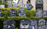 In this Aug. 9, 2021, file photo, Jayde Newton helps to set up cardboard gravestones with the names of victims of opioid abuse outside the courthouse where the Purdue Pharma bankruptcy is taking place in White Plains, N.Y. A federal bankruptcy judge on Wednesday, Sept. 1, gave conditional approval to a sweeping, potentially $10 billion plan submitted by OxyContin maker Purdue Pharma to settle a mountain of lawsuits over its role in the opioid crisis that has killed a half-million Americans over the past two decades. (AP Photo/Seth Wenig, File)