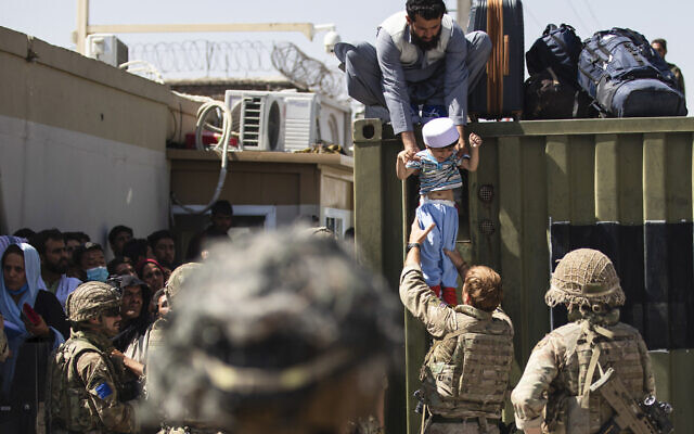 In this August 26, 2021, file image provided by the US Army, an Afghan man hands his child to a British Paratrooper assigned to 2nd Battalion, Parachute Regiment while a member of 1st Brigade Combat Team, 82nd Airborne Division conducts security at Hamid Karzai International Airport in Kabul, Afghanistan. (US Army via AP, File)