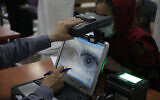 An employee scans the eyes of a woman for biometric data needed to apply for a passport, at the passport office in Kabul, Afghanistan, June 30, 2021. (AP Photo/Rahmat Gul, File)