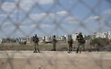 Israeli soldiers stand guard near a damaged section of the border fence, near the West Bank village of Jalameh, September 6, 2021. (AP/Nasser Nasser)