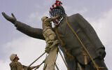 Cpl. Edward Chin of the US 3rd Battalion, 4th Marines Regiment, covers the face of a statue of Saddam Hussein with an American flag before toppling the statue in downtown Baghdad, Iraq, April 9, 2003. (Jerome Delay/AP)