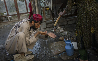 A displaced Afghan man drinks from a water tank at an internally displaced persons camp in Kabul, Afghanistan, September 13, 2021. (Bernat Armangue/AP) A displaced Afghan man drinks from a water tank at an internally displaced persons camp in Kabul, Afghanistan, September 13, 2021. (Bernat Armangue/AP)