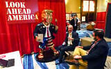 In this Feb. 26, 2021, file photo, Look Ahead America sponsor Matt Braynard, center, talks to conference attendees at his booth in the merchandise show with a statue of former president Donald Trump at the Conservative Political Action Conference (CPAC) in Orlando, Fla. (AP Photo/John Raoux, File)
