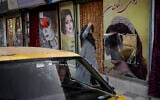A woman walks past beauty salons with window decorations which have been defaced in Kabul, Afghanistan, Sept. 12, 2021 (AP Photo/Bernat Armangue)