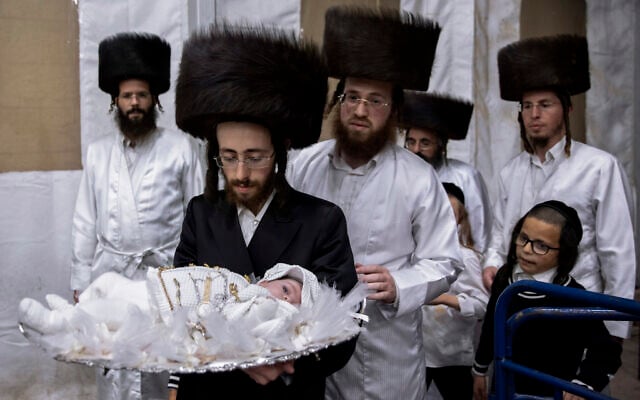 Yaakov Tabersky, carries his 30-day-old son Yossef, the great grandchild of the chief rabbi of the Lelov Hassidic dynasty, during the "Pidyon Haben" ceremony in Beit Shemesh, Israel, on September 16, 2021. (AP/Oded Balilty)