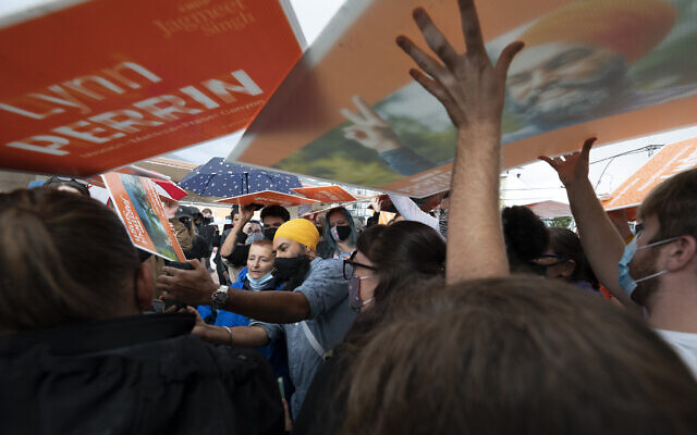 New Democratic Party supporters use signs as rain shields, as NDP Leader Jagmeet Singh greets people during a campaign stop in Pitt Meadows, British Columbia, on Sunday, September 19, 2021. (Jonathan Hayward/The Canadian Press via AP) New Democratic Party supporters use signs as rain shields, as NDP Leader Jagmeet Singh greets people during a campaign stop in Pitt Meadows, British Columbia, on Sunday, September 19, 2021. (Jonathan Hayward/The Canadian Press via AP)