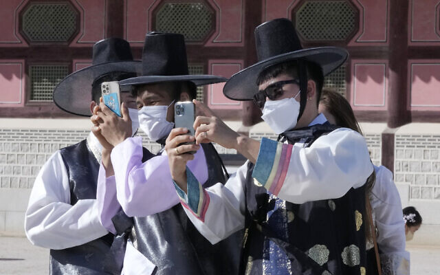 Men wearing face masks as a precaution against the coronavirus take photos as they visit to celebrate Chuseok holidays, the Korean version of Thanksgiving Day, at the Gyeongbok Palace in Seoul, South Korea, on September 22, 2021. (AP Photo/Ahn Young-joon)