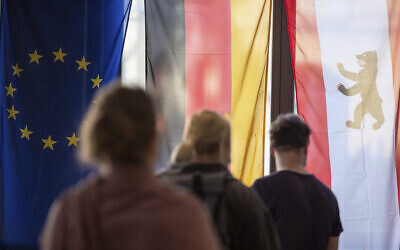 Voters stand in front of a European, German and Berlin flag at a polling station to cast their votes in Berlin, Germany, Sunday,  Sept. 26, 2021. German elect a new national parliament. (Sebastian Gollnow/dpa via AP)