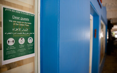 A sign at the entrance to a shop in Jerusalem, allowing entry to Green Pass holders only, and regulations concerning masks, social distancing, on August 4, 2021. (Yonatan Sindel/Flash90)