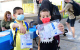 Kids at a school in Tel Aviv hold up antigen coronavirus testing kits, on August 30, 2021. (Avshalom Sassoni/Flash90)