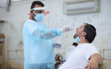 A health worker takes a swab sample from a man at a coronavirus testing site in the northern city of Safed, August 31, 2021. (David Cohen/Flash90)