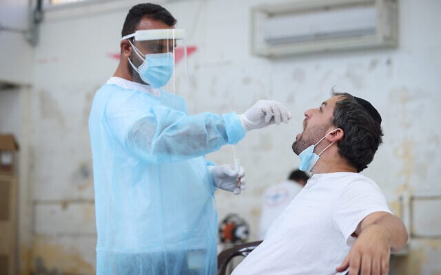 A health worker takes a swab sample from a man at a coronavirus testing site in the northern city of Safed, August 31, 2021. (David Cohen/Flash90) A health worker takes a swab sample from a man at a coronavirus testing site in the northern city of Safed, August 31, 2021. (David Cohen/Flash90)