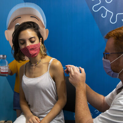 An Israeli woman receives a third dose of the COVID-19 vaccine at a clinic in Jerusalem, September 20, 2021 (Olivier Fitoussi/Flash90)