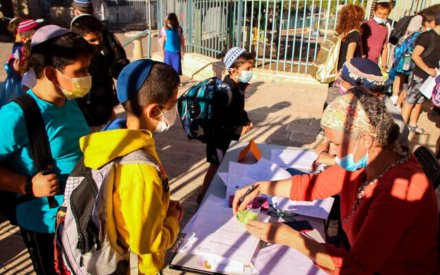 Young Israeli students have their antigen test results checked as they arrive for their first day of school after the holidays, at Aseh Hayil school in the West Bank settlement of Efrat, September 30, 2021 (Gershon Elinson/Flash90) Young Israeli students have their antigen test results checked as they arrive for their first day of school after the holidays, at Aseh Hayil school in the West Bank settlement of Efrat, September 30, 2021 (Gershon Elinson/Flash90)