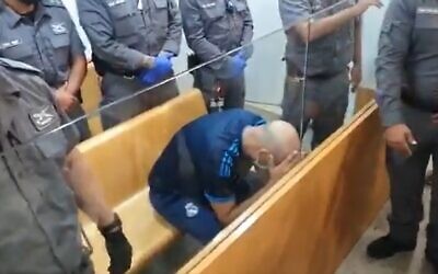 Nasim Sah, the suspect in a Nahariya car-ramming that killed a police volunteer, covers his face during a hearing at the Haifa Magistrate's Court, on September 22, 2021. (Screenshot/Twitter)