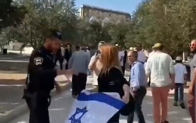 A police officer confiscates an Israeli flag from a woman on the Temple Mount, September 27. 2021. (Video screenshot) A police officer confiscates an Israeli flag from a woman on the Temple Mount, September 27. 2021. (Video screenshot)