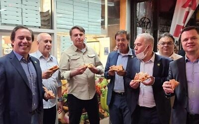 Brazilian President Jair Bolsonaro, center left, eats pizza on a New York sidewalk in a photo uploaded to social media on September 20, 2021. (Tourism Minister Gilson Machado/Instagram)
