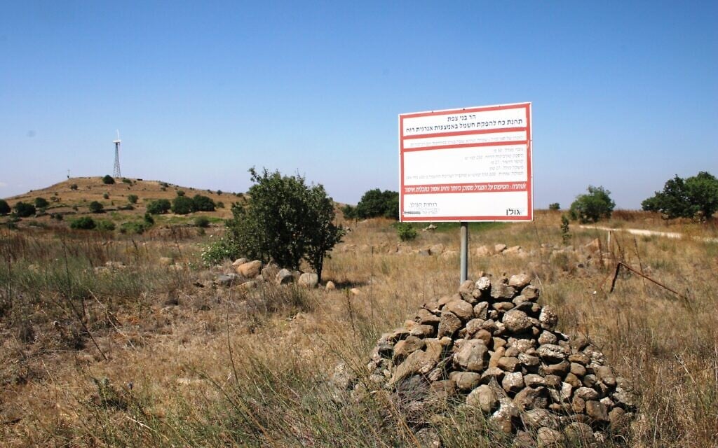 A sign explaining the energy contribution of the wind turbine dedicated to Simha Zeira in the Golan Heights, with the turbine memorial in the background. (Shmuel Bar-Am)