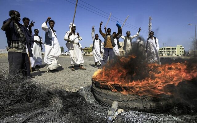 Members of the Beja ethnic group of eastern Sudan gather around burning tires as they demonstrate outside the Osman Digna port in Sudan's northeastern Red Sea coastal city of Suakin on October 9, 2021 (ASHRAF SHAZLY / AFP) Members of the Beja ethnic group of eastern Sudan gather around burning tires as they demonstrate outside the Osman Digna port in Sudan's northeastern Red Sea coastal city of Suakin on October 9, 2021 (ASHRAF SHAZLY / AFP)