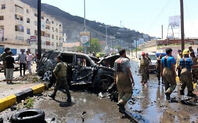 Yemeni security forces and rescue teams gather around the skeleton of a burnt car following an explosion that hit Yemen's southern port city of Aden, on October 10, 2021. (Saleh Al-OBEIDI / AFP)