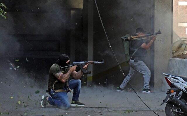 Shiite fighters from Hezbollah and Amal movements take aim with (L to R) a Kalashnikov assault rifle and a rocket-propelled grenade launcher amidst clashes in the area of Tayouneh, in the southern suburb of the capital Beirut, on October 14, 2021. (Ibrahim Amro/AFP)