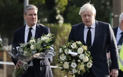 Britain's Prime Minister Boris Johnson (right) and Britain's main opposition Labour Party leader Keir Starmer carry floral tributes as they arrive at the scene of the fatal stabbing of Conservative British lawmaker David Amess, at Belfairs Methodist Church in Leigh-on-Sea, a district of Southend-on-Sea, in southeast England, on October 16, 2021 (Tolga Akmen/AFP)