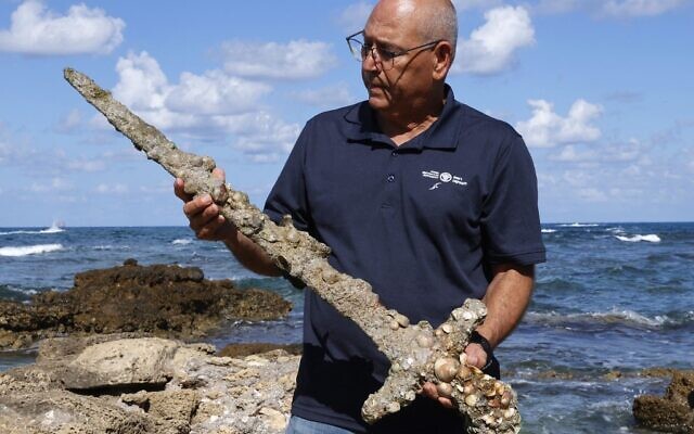 Jacob Sharvit of the Israel Antiquities Authority displays an ancient one-meter-long sword that experts say dates back to the Crusader-era and is believed to have belonged to a Crusader, at the beach in Caesarea, on October 19, 2021 days after being discovered by a local diver. (JACK GUEZ / AFP)