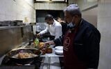 Moin (R) and Mustapha Abu Hassira work in the kitchen of Roma fish restaurant owned by the Abu Hassira family in Gaza City, on October 23, 2021. (MOHAMMED ABED / AFP)