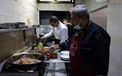 Moin (R) and Mustapha Abu Hassira work in the kitchen of Roma fish restaurant owned by the Abu Hassira family in Gaza City, on October 23, 2021. (MOHAMMED ABED / AFP)
