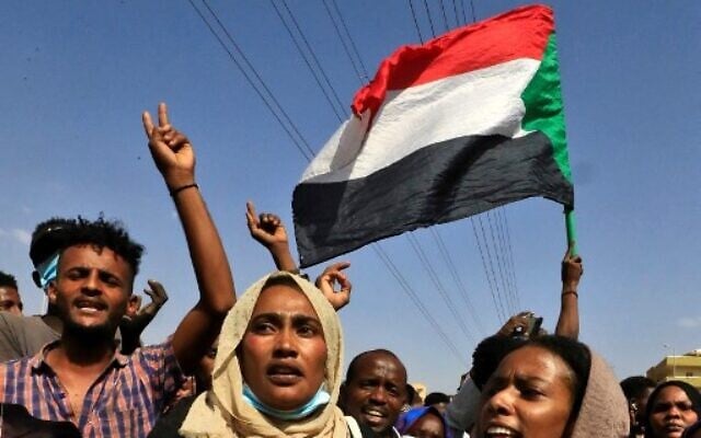 Sudanese protesters flash victory signs and lift national flags as they demonstrate on 60th Street in the capital Khartoum, to denounce overnight detentions by the army of government members, on October 25, 2021. (Photo by AFP) Sudanese protesters flash victory signs and lift national flags as they demonstrate on 60th Street in the capital Khartoum, to denounce overnight detentions by the army of government members, on October 25, 2021. (Photo by AFP)