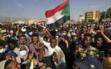 Sudanese protesters lift national flags as they rally in the capital Khartoum, to denounce overnight detentions by the army of government members, on October 25, 2021 (Photo by AFP)
