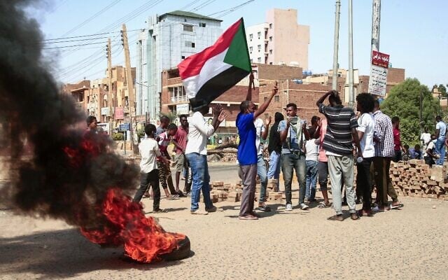 Sudanese demonstrators lift national flags and burn tires on a street in the capital Khartoum, on October 26, 2021, as they protest a military coup that overthrew the transition to civilian rule.(AFP) Sudanese demonstrators lift national flags and burn tires on a street in the capital Khartoum, on October 26, 2021, as they protest a military coup that overthrew the transition to civilian rule.(AFP)
