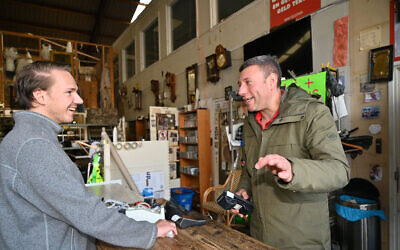 Gideon Italiaander (right) charges a customer's debit card at his shop in Amsterdam, the Netherlands, on October 11, 2021. (Cnaan Liphshiz/JTA)