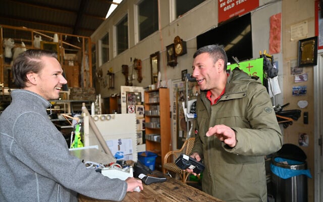Gideon Italiaander (right) charges a customer's debit card at his shop in Amsterdam, the Netherlands, on October 11, 2021. (Cnaan Liphshiz/JTA)