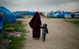 A foreign national married to an Islamic State member walks with their son at Camp Roj in north Syria, March 27, 2019. (Maya Alleruzzo/AP)