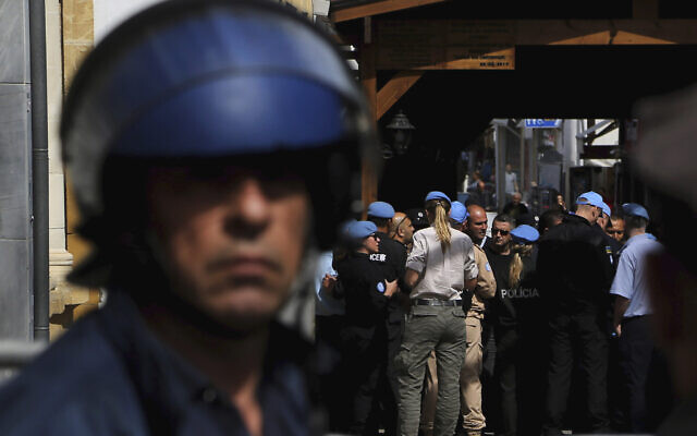A Greek police officer, foreground, stands guard as UN peacekeepers block the closed crossing point in the divided capital of Nicosia, Cyprus, on March 9, 2020. (AP Photo/Petros Karadjias)
