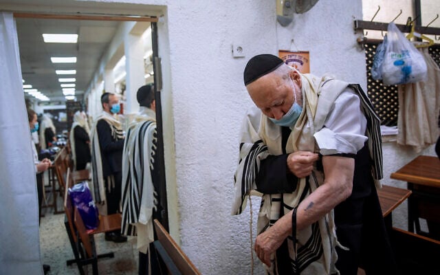Holocaust survivor Yehoshua Datsinger places tefillin on his arm above the Auschwitz concentration camp identification number tattoo, during morning prayer at a synagogue, in Bnei Brak, Israel, September 21, 2020. (Oded Balilty/AP) Holocaust survivor Yehoshua Datsinger places tefillin on his arm above the Auschwitz concentration camp identification number tattoo, during morning prayer at a synagogue, in Bnei Brak, Israel, September 21, 2020. (Oded Balilty/AP)