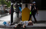 In this July 17, 2020 file photo, a woman looks at a homeless Lebanese man sleeping on the ground in Hamra street, in Beirut, Lebanon (AP Photo/Hassan Ammar, File)