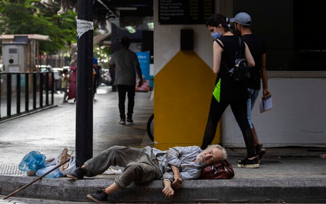 In this July 17, 2020 file photo, a woman looks at a homeless Lebanese man sleeping on the ground in Hamra street, in Beirut, Lebanon (AP Photo/Hassan Ammar, File) In this July 17, 2020 file photo, a woman looks at a homeless Lebanese man sleeping on the ground in Hamra street, in Beirut, Lebanon (AP Photo/Hassan Ammar, File)