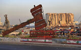 In this Aug. 4, 2021 file photo, a monument that represents justice stands in front of towering grain silos that were gutted in the massive August 2020 explosion at the port in Beirut, Lebanon (AP Photo/Hussein Malla, File)