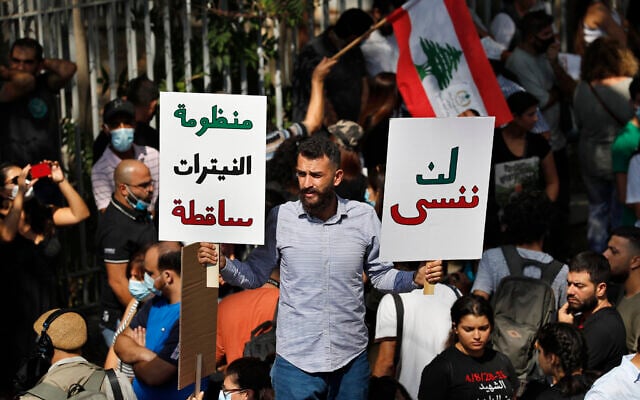 A protester holds Arabic placards that reads: 'Will not forget, right, down with the system of nitrates,' outside a court building during a demonstration of solidarity with Judge Tarek Bitar who is investigating last year's deadly seaport blast, in Beirut, Lebanon, Wednesday, September 29, 2021. (AP Photo/Hussein Malla) A protester holds Arabic placards that reads: 'Will not forget, right, down with the system of nitrates,' outside a court building during a demonstration of solidarity with Judge Tarek Bitar who is investigating last year's deadly seaport blast, in Beirut, Lebanon, Wednesday, September 29, 2021. (AP Photo/Hussein Malla)