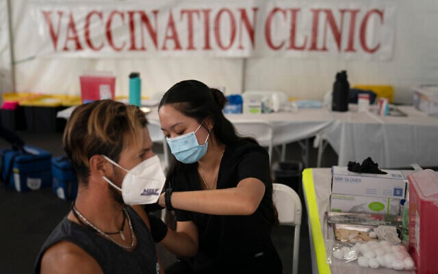 In this Aug. 28, 2021, file photo, registered nurse, Noleen Nobleza, center, inoculates Julio Quinones with a COVID-19 vaccine at a clinic set up in the parking lot of CalOptima in Orange, Calif. (AP Photo/Jae C. Hong)