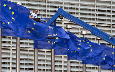 A worker on a lift adjusts the EU flags in front of EU headquarters in Brussels, on June 23, 2016. (AP Photo/Virginia Mayo, File)