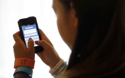 In this June 4, 2012, file photo, an unidentified 11-year-old girl logs into Facebook on her iPhone at her home in Palo Alto, Calif.  (AP Photo/Paul Sakuma, File)