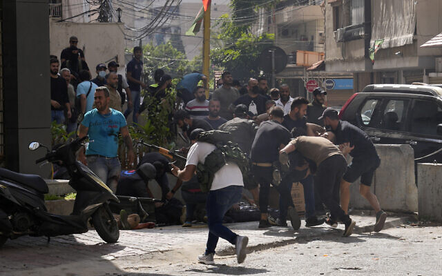 Supporters of a Shiite group allied with Hezbollah help an injured comrade during armed clashes that erupted during a protest in the southern Beirut suburb of Dahiyeh, Lebanon, October 14, 2021. (AP Photo/Hassan Ammar) Supporters of a Shiite group allied with Hezbollah help an injured comrade during armed clashes that erupted during a protest in the southern Beirut suburb of Dahiyeh, Lebanon, October 14, 2021. (AP Photo/Hassan Ammar)