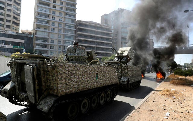Lebanese army soldiers stand guard on their armored vehicle as supporters of the Shiite Hezbollah and Amal groups burn garbage containers to block a road during a protest in Beirut, Lebanon, on October 14, 2021. (AP Photo/Bilal Hussein) Lebanese army soldiers stand guard on their armored vehicle as supporters of the Shiite Hezbollah and Amal groups burn garbage containers to block a road during a protest in Beirut, Lebanon, on October 14, 2021. (AP Photo/Bilal Hussein)